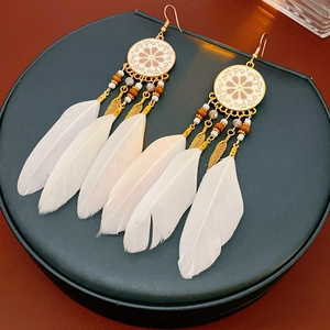 Détail de boucles d'oreilles attrape-rêves avec plumes blanches et perles dorées