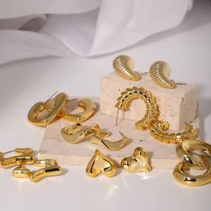 Detailed close-up of various gold-plated earrings on travertine stone display