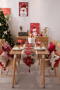 Dettaglio del runner natalizio intrecciato con motivi di stelle di Natale rosse e frange