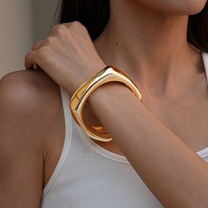 Close-up of chunky gold geometric acrylic bangle with a polished mirror finish on wrist