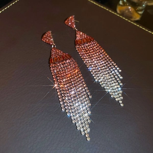 Close-up of cascading rhinestone fringe earrings with pink to silver gradient effect
