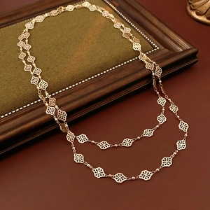 Detail of vintage gold layered necklace with clover motif on green velvet background