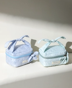 Close-up of floral jacquard makeup bags in light blue and mint green with bow handles