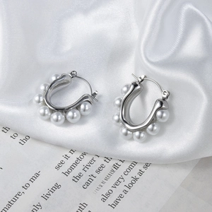Elegant silver U-shaped earrings with white pearls on white silk background