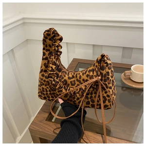 Détail du sac cabas léopard avec poignées froncées sur une table en bois