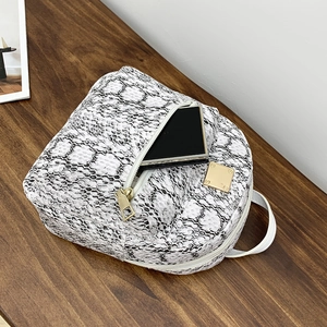 Close-up of black and white snakeskin pattern backpack with premium gold zipper details