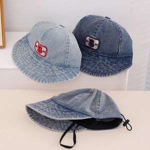 Detail of embroidered 'BEST' logo and adjustable windproof cord on denim bucket hat