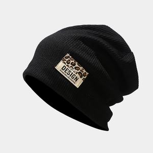 Détail du bonnet en maille côtelée noire avec écusson léopard et design texte