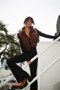 Detail of a brown cropped quilted puffer vest with stand collar and zipper closure
