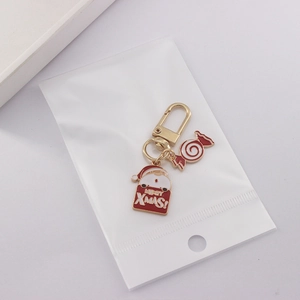 Detailed view of Merry Xmas Santa and candy cane enamel pendants on a gold keychain