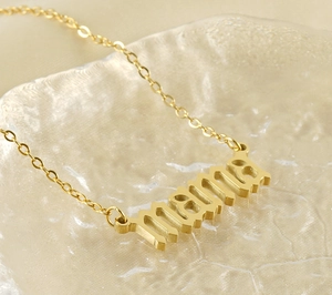 Gros plan du collier avec pendentif mama en or 18k sur fond en verre texturé
