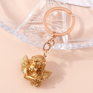 Detailed close-up of golden Cupid angel keychain with harp on a textured glass plate