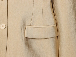 Macro-opname van een champagne satijnen blazer met zakdetail en bijpassende knopen