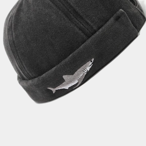 Close-up of a black washed brimless cap featuring a detailed gray shark embroidery detail