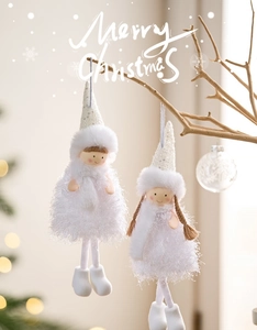 Close-up of plush Christmas angel ornaments hanging on branches with warm bokeh lights