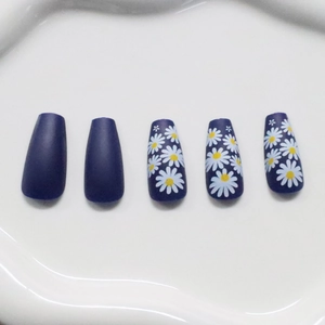 Blue matte press-on coffin nails with white daisy floral art on a white tray