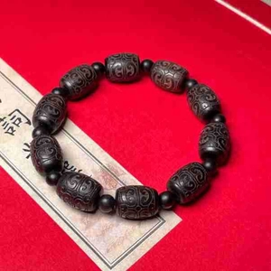 Macro detail of ebony wood barrel beads with exquisite carved auspicious cloud patterns