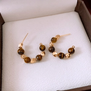 Macro detail of 18k gold plated tiger eye earrings with brown beads in jewelry box