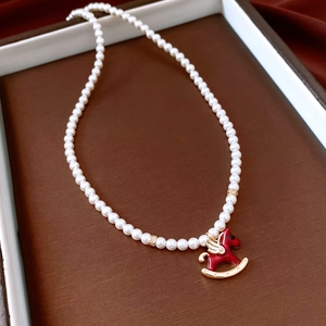 Detail of red winged horse pendant on a white pearl necklace with gold accents