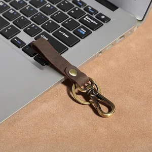 Vintage dark brown leather keychain with bronze carabiner on laptop keyboard
