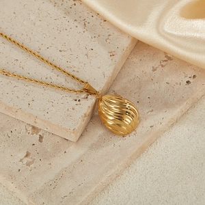 Macro detail of golden oval pendant with wave texture on a twisted rope chain