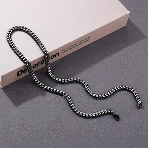 Close-up of a masculine black stainless steel Cuban link chain necklace on a book