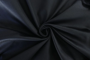 Macro shot of high-quality black satin fabric texture with elegant silky spiral folds
