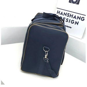 Detail of navy blue travel bag featuring brown piping, black handles and metal buckles