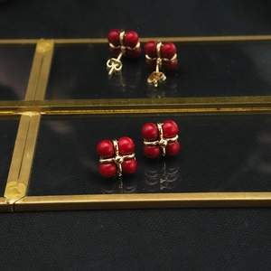 Detailed shot of vintage gold earrings with four red beads on a display stand