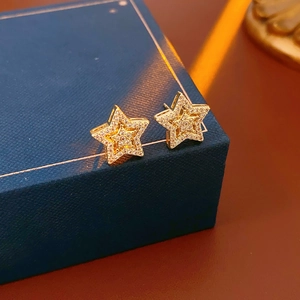 Macro view of gold star stud earrings with pave zircon on a dark blue jewelry gift box