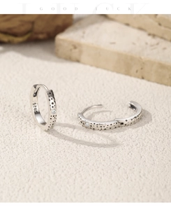 Macro detail of S925 sterling silver hoop earrings with star patterns and clear zircon