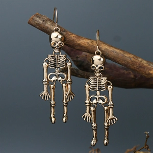 Macro shot of bronze skeleton skull earrings hanging on a dark twig with punk gothic style