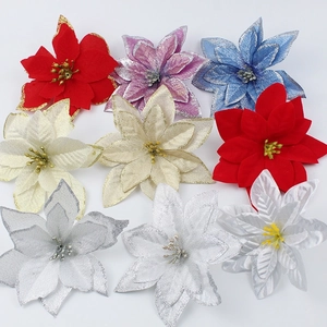 Flat lay of artificial poinsettias in various colors with glittered edges for Christmas