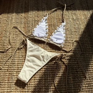Flat lay of a two-piece bikini with contrast grommets and tie-up details on woven rug