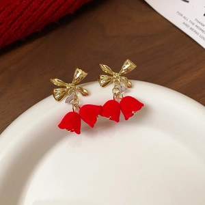 Detail of red velvet flower earrings with golden bow accents and crystal details