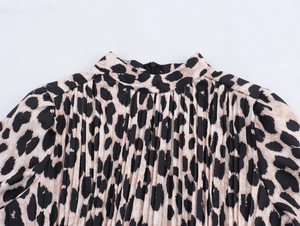 Detail of leopard print pleated dress featuring elegant neckline and fabric texture
