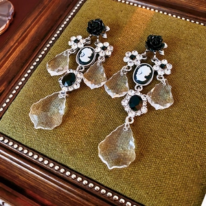 Detail of vintage French style drop earrings with black rose cameo and green gemstone