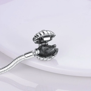 Macro detail of silver shell clasp opening on a snake chain bracelet with hinge detail