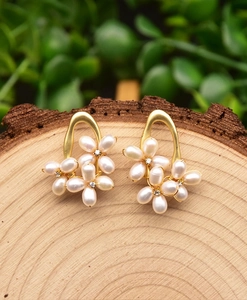 Macro detail of handmade 925 silver floral pearl earrings on natural wooden texture