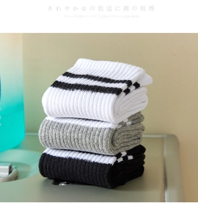 Detailed view of three pairs of cotton striped socks in white, gray, and black colors