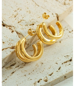 Macro shot of 18K gold plated double hoop earrings on a textured stone surface