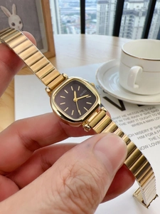 Close-up of a vintage square gold quartz watch with a black dial and metal chain strap