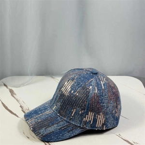 Detail of rose gold sequins on blue denim baseball cap over white marble surface