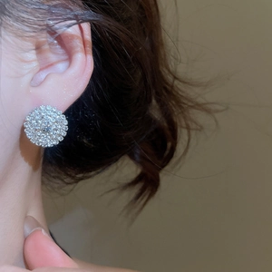 Close-up of sparkling round diamond stud earrings worn by a model in silver finish