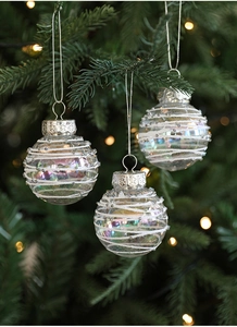 Close-up of iridescent Christmas balls with white glitter swirls on a festive tree branch