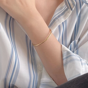 Minimalist S925 sterling silver open bangle in gold finish worn on wrist over a striped shirt