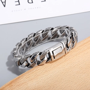 Macro shot of silver Cuban chain bracelet with Greek meander patterns and folding clasp
