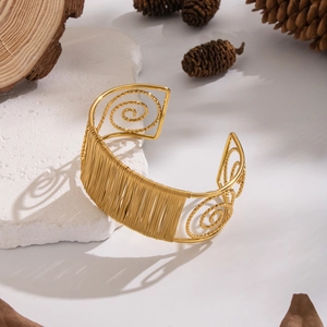 Macro detail of a gold hollow wire mesh open cuff bracelet on a natural stone surface