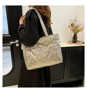 Macro detail of silver quilted tote bag with puffer texture and fashion label