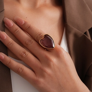 Gros plan d'une grande bague cœur en zircone violette sertie d'or portée au doigt